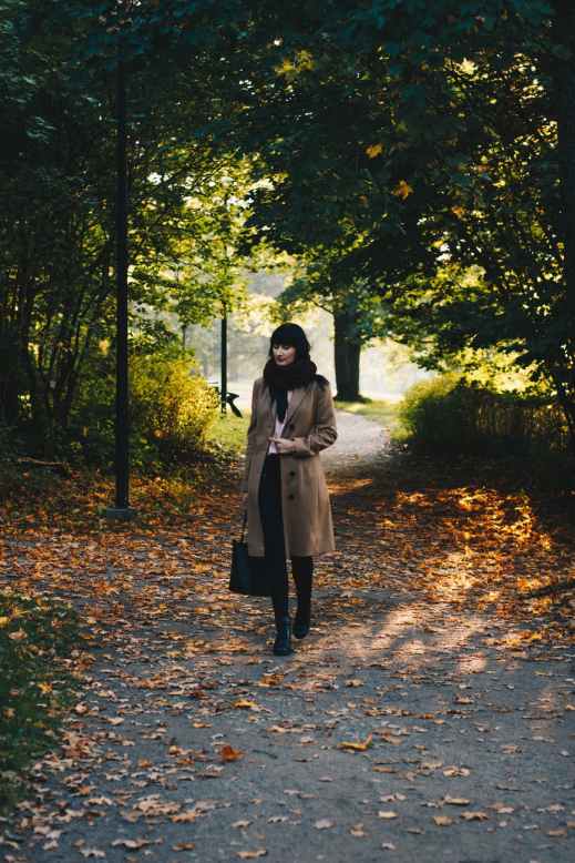woman in coat walking in park in autumn